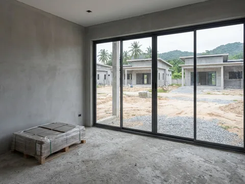 A room inside the villa, unfinished, with glazing installed and floor tiles stacked